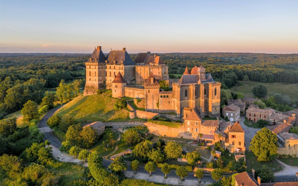 Vue aérienne du château de Biron et de son village, au printemps